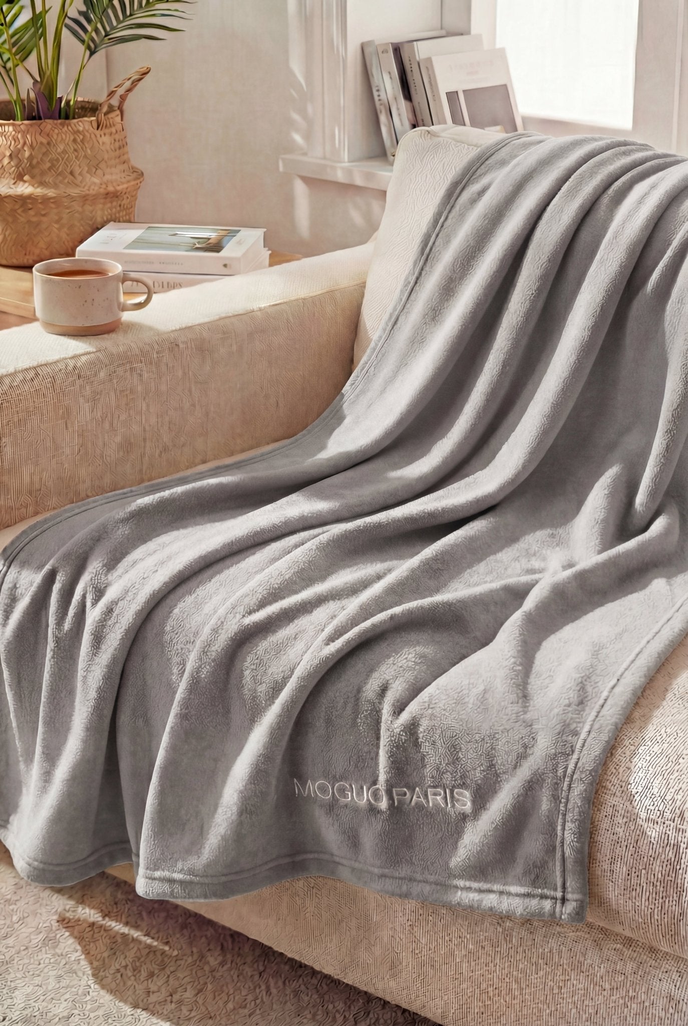 Mannequin femme en tenue d'intérieur, relaxée sur un canapé avec le plaid gris XL ultra moelleux.