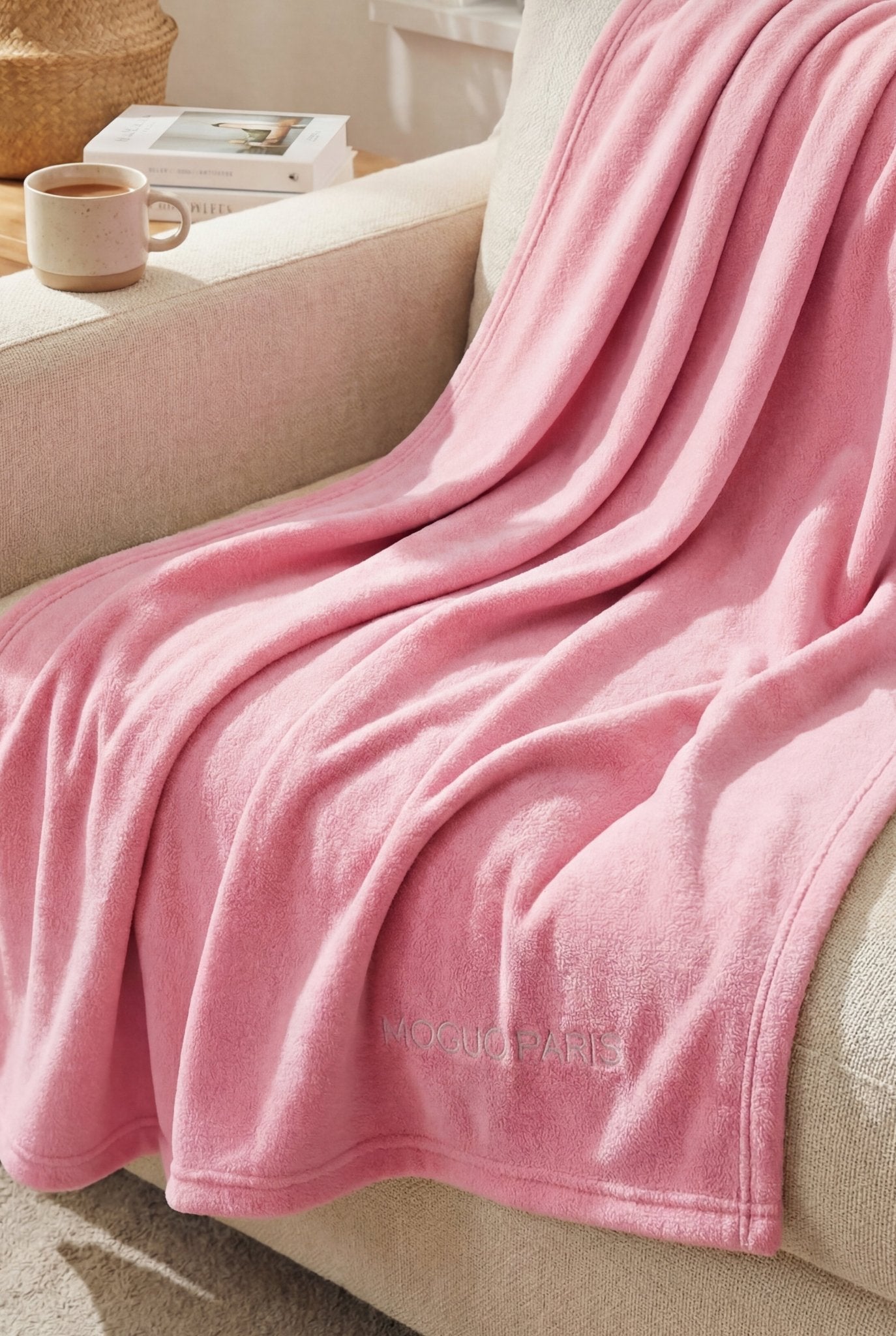 Femme se relaxant sur un canapé, enveloppée dans le grand plaid rose cocooning XL.