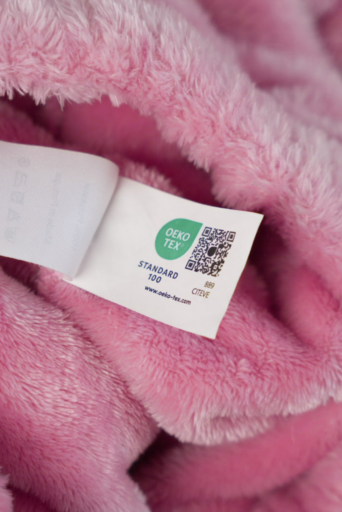 Femme se relaxant sur un canapé avec le sweat signature rose, pièce de homewear de luxe.